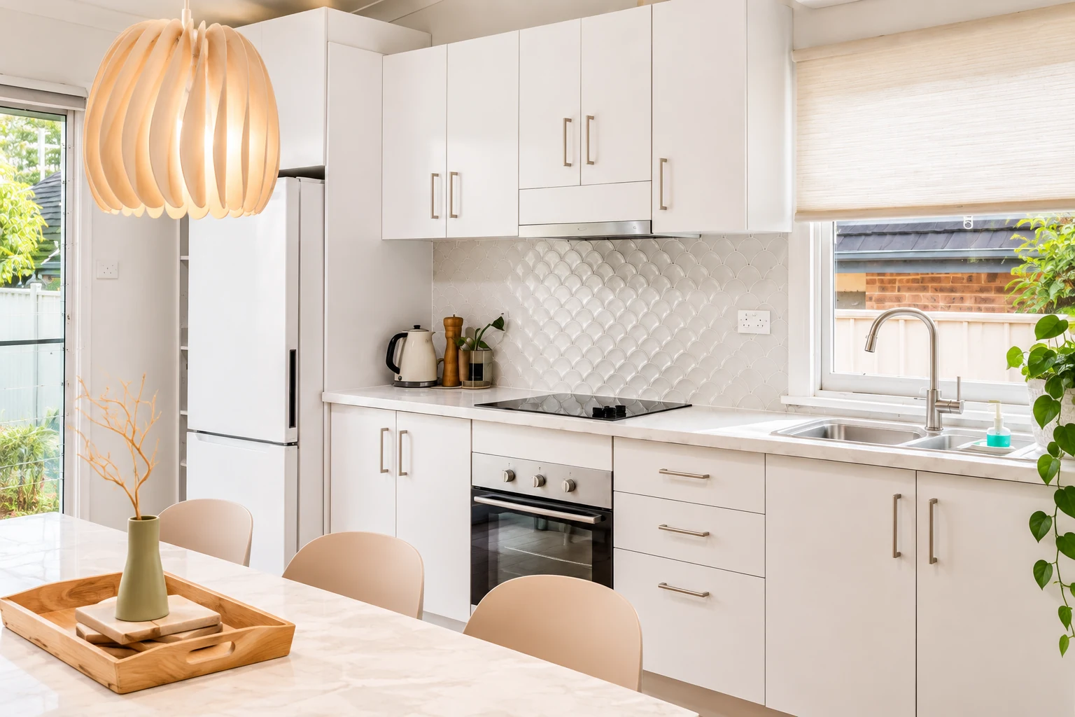 Bright full kitchen with dining table and backyard view at Kos Koliba